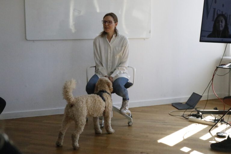 Sandra Cameron leading a workshop session with a dog beside her.